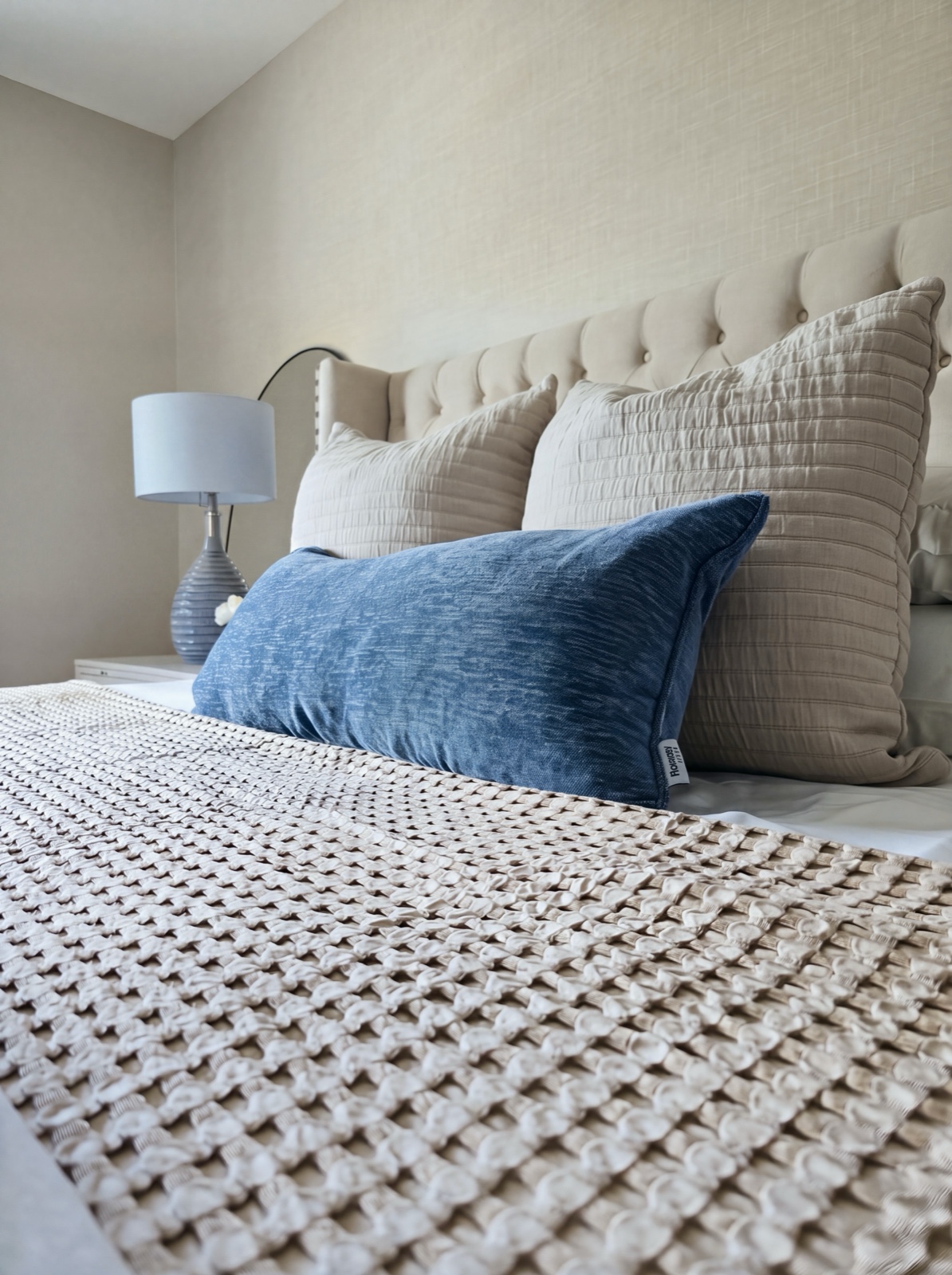 Bed styling detail with quilted shams, chenille lumbar, and waffle-weave runner