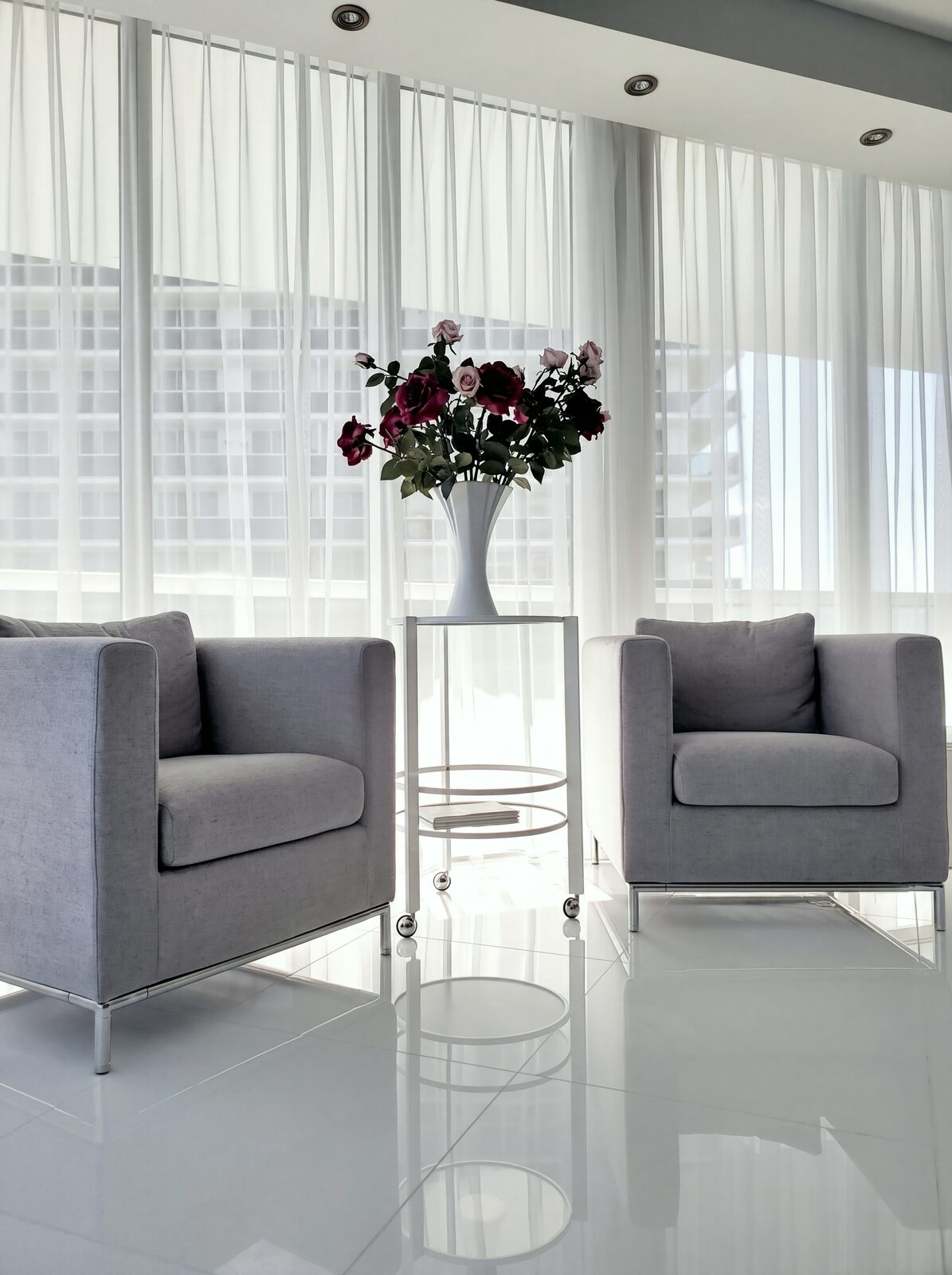 Pair of armchairs with roses against backlit sheer curtains