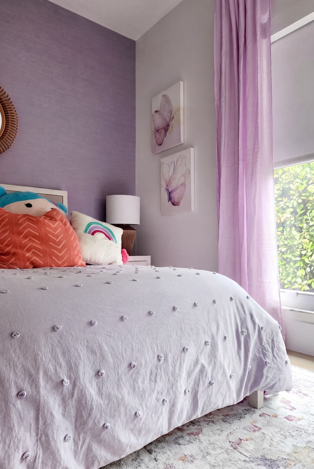 Kids' bedroom with lavender grasscloth accent wall and rattan mirror