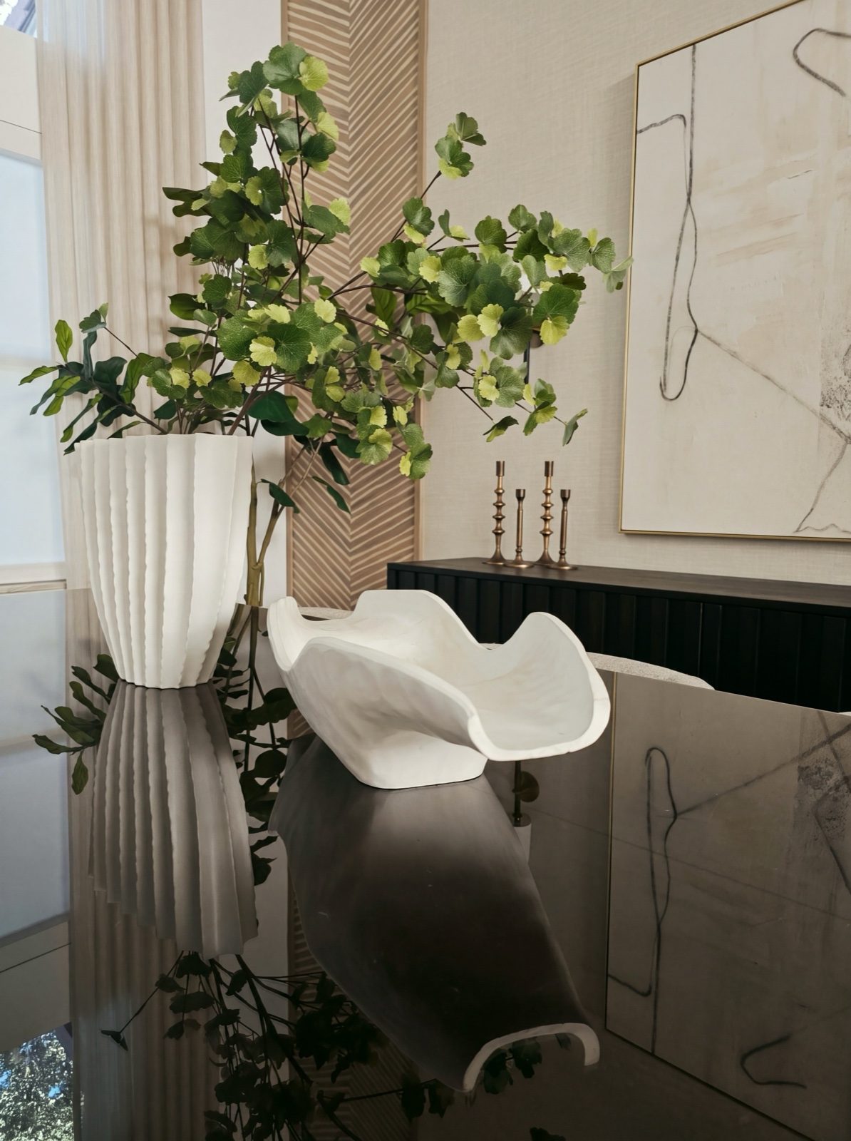 Sculptural white vessels reflected in a black lacquer table