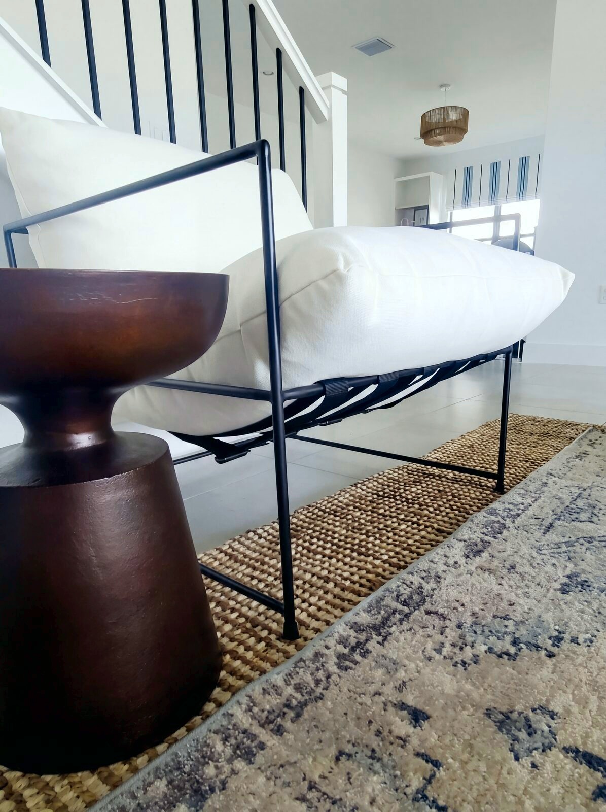 Black metal accent chair over layered jute and vintage rugs